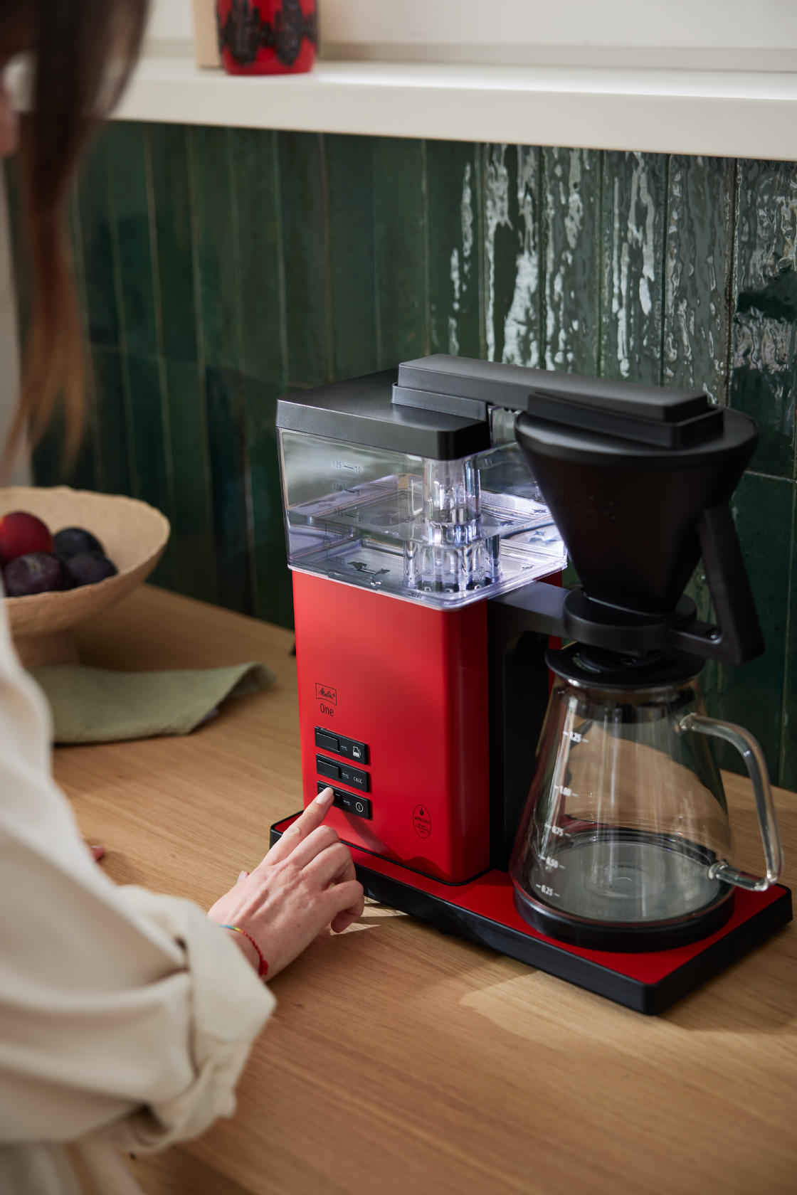 Person trykker på en knap på den røde Melitta ONE® filterkaffemaskine