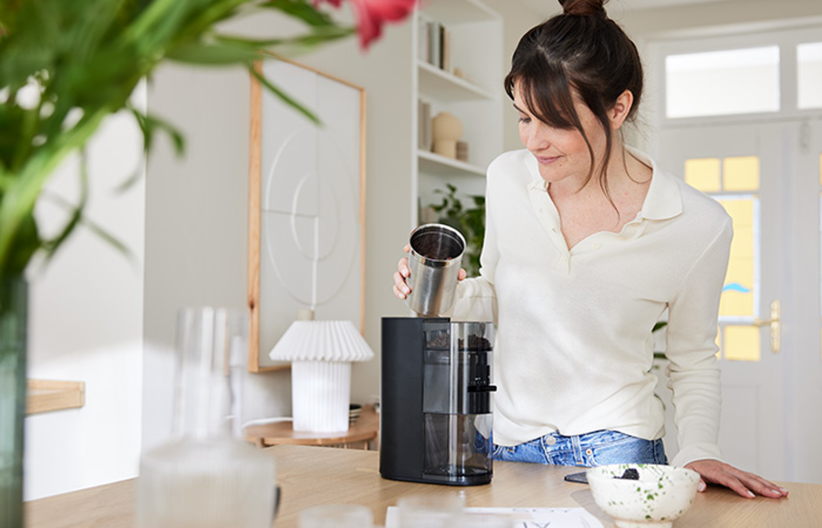 Melitta Linea® Kaffeemühle in moderner Küche beim Einfüllen von Kaffeebohnen.
