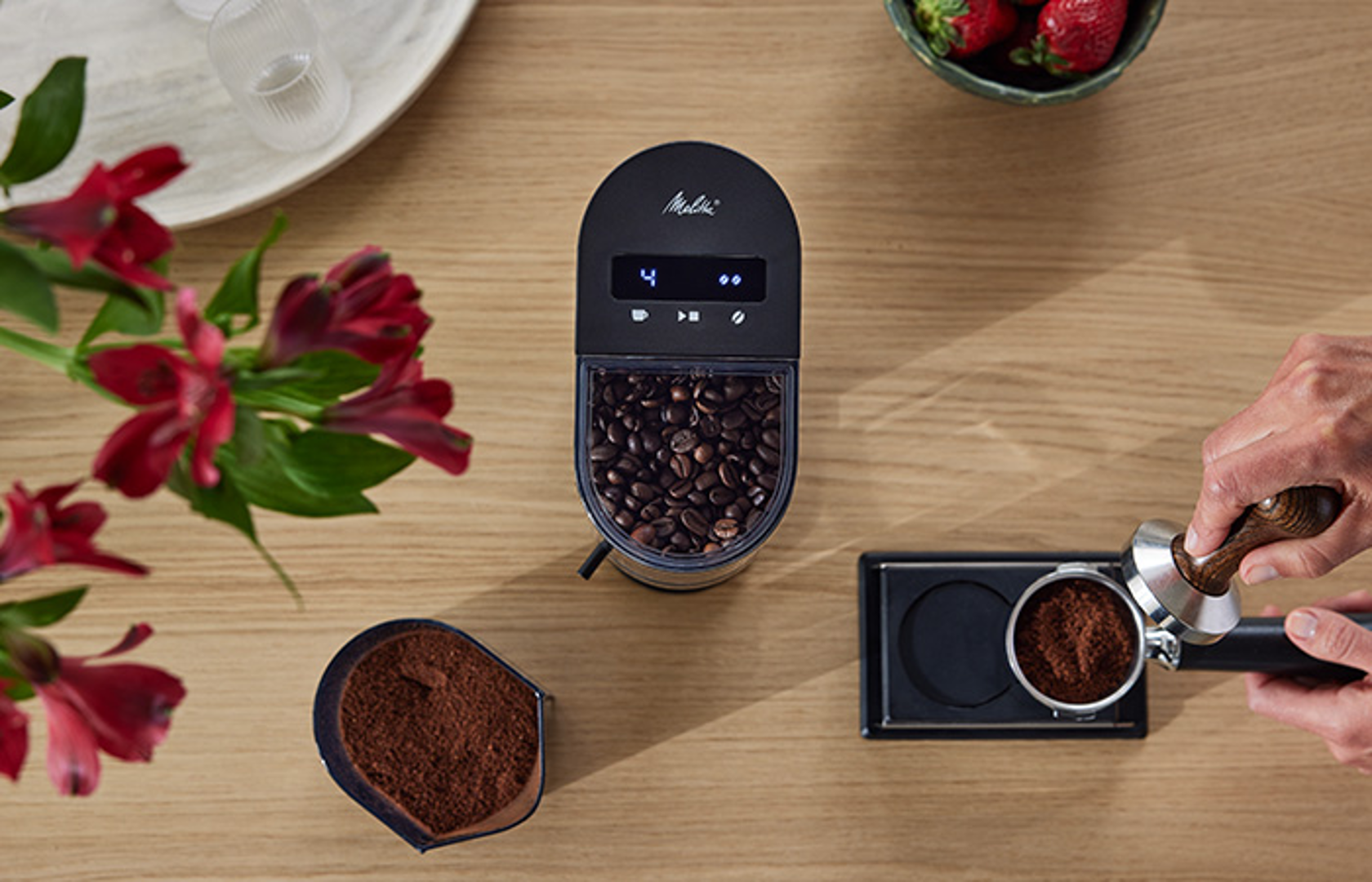 Melitta Linea® Kaffeemühle von oben mit gemahlenem Kaffee und Siebträger auf Holztisch.