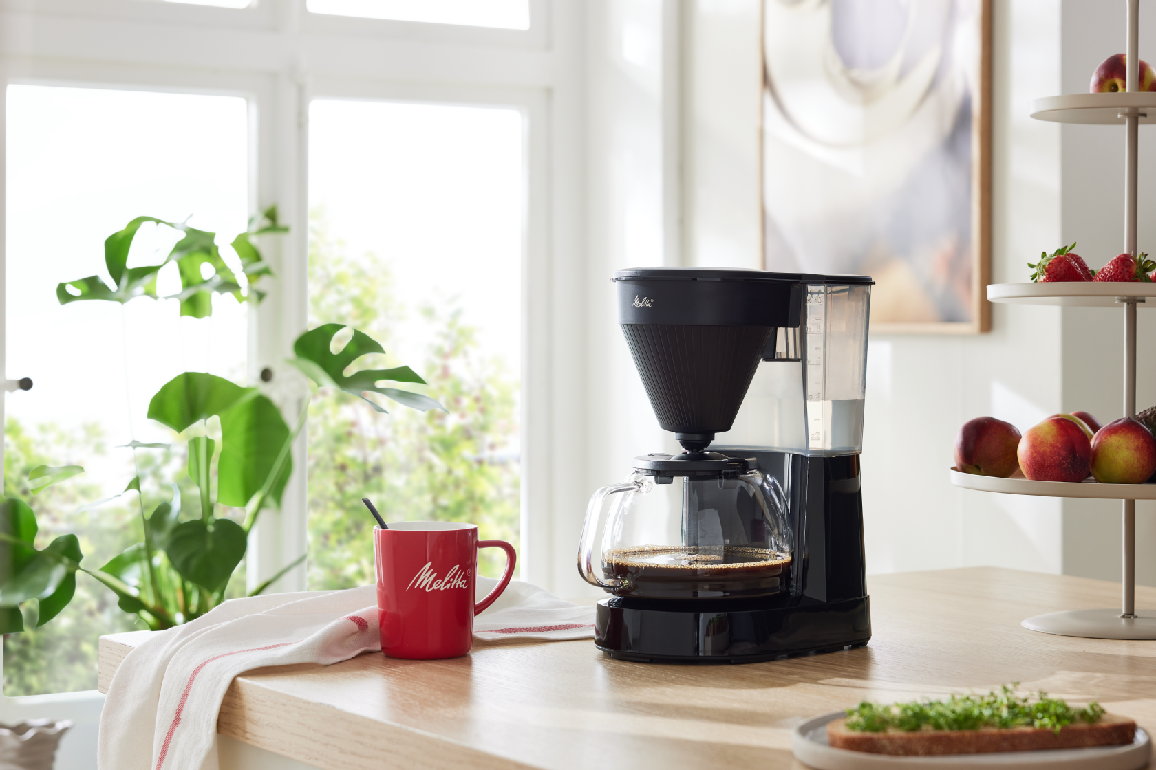 Melitta® Easy Next Filterkaffeemaschine mit Glaskanne auf einem Küchentisch in heller Wohnküche