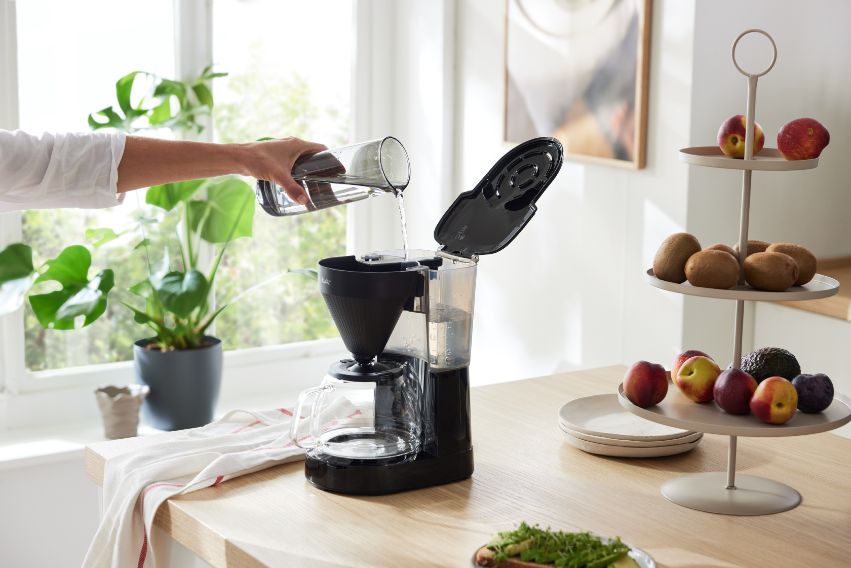 Melitta® Easy Next Filterkaffeemaschine beim Befüllen mit Wasser in einer hellen Küche
