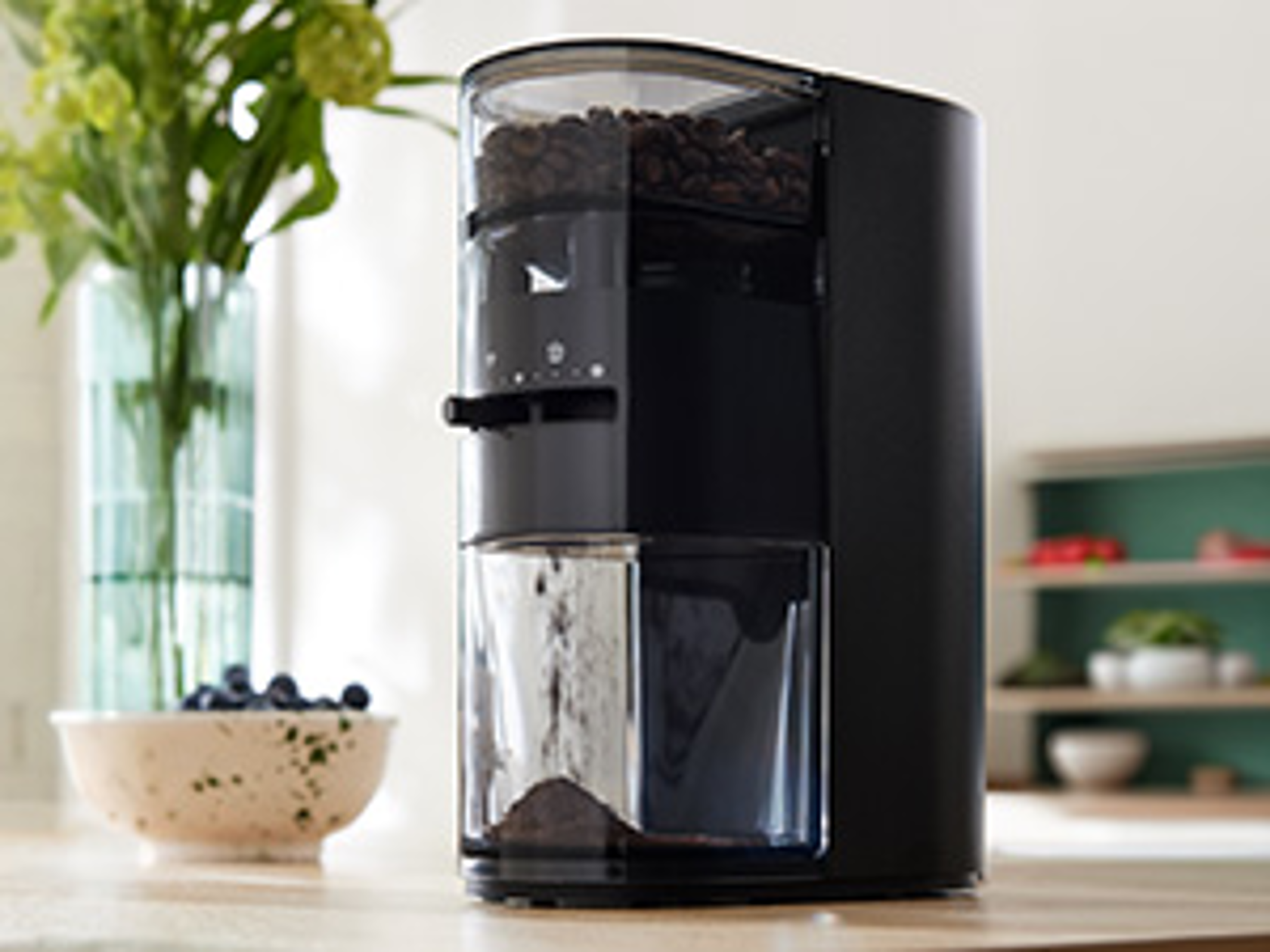Melitta Linea® Kaffeemühle in Schwarz auf einer Küchenarbeitsplatte mit Bohnenbehälter und Auffangbehälter für gemahlenen Kaffee.