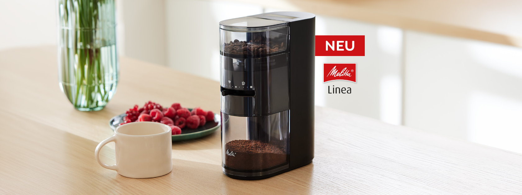 Melitta Linea Kaffeemühle mit Kaffeebohnen und gemahlenem Kaffee neben einer Tasse auf der Küchenarbeitsplatte