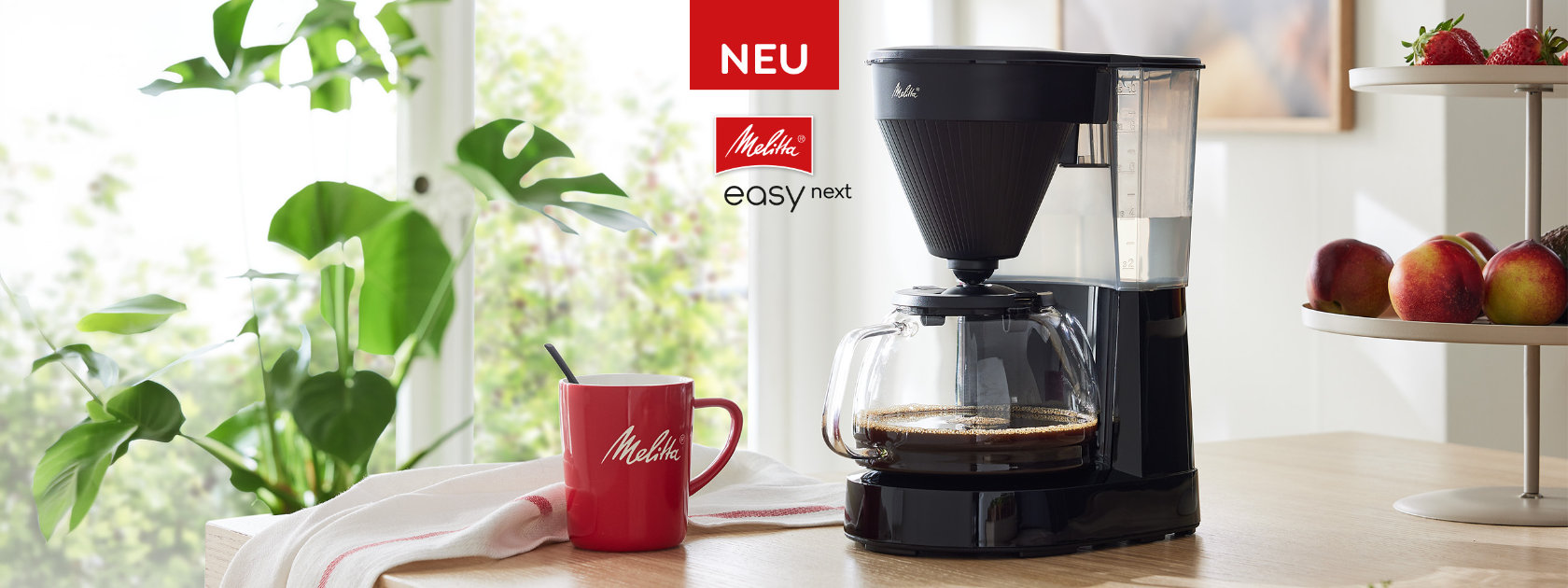 Neue Melitta® Easy Next Filterkaffeemaschine mit Glaskanne und roter Melitta® Kaffeetasse in moderner Küche