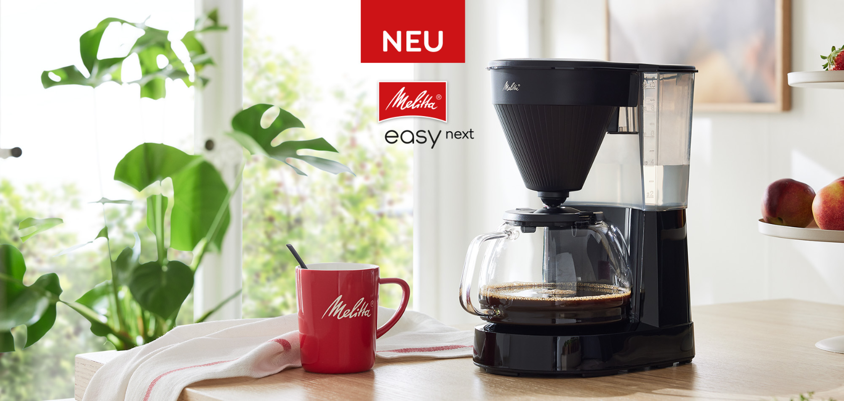 Neue Melitta® Easy Next Filterkaffeemaschine mit Glaskanne und roter Melitta® Kaffeetasse in moderner Küche