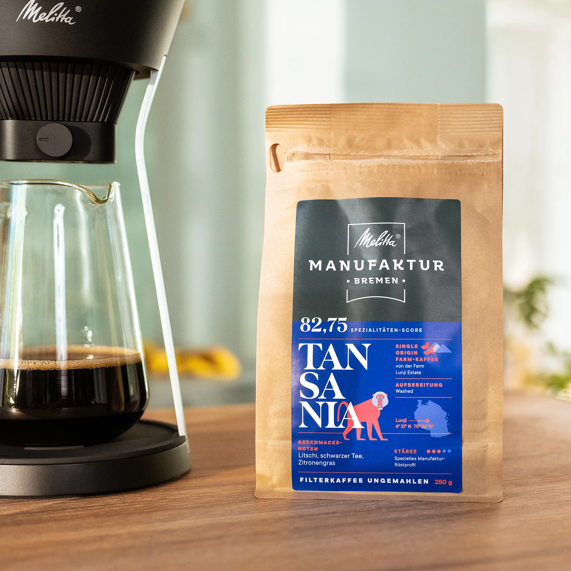 eine Packung Melitta Manufakturkaffee Tansania steht neben einer Melitta Kaffeemaschine