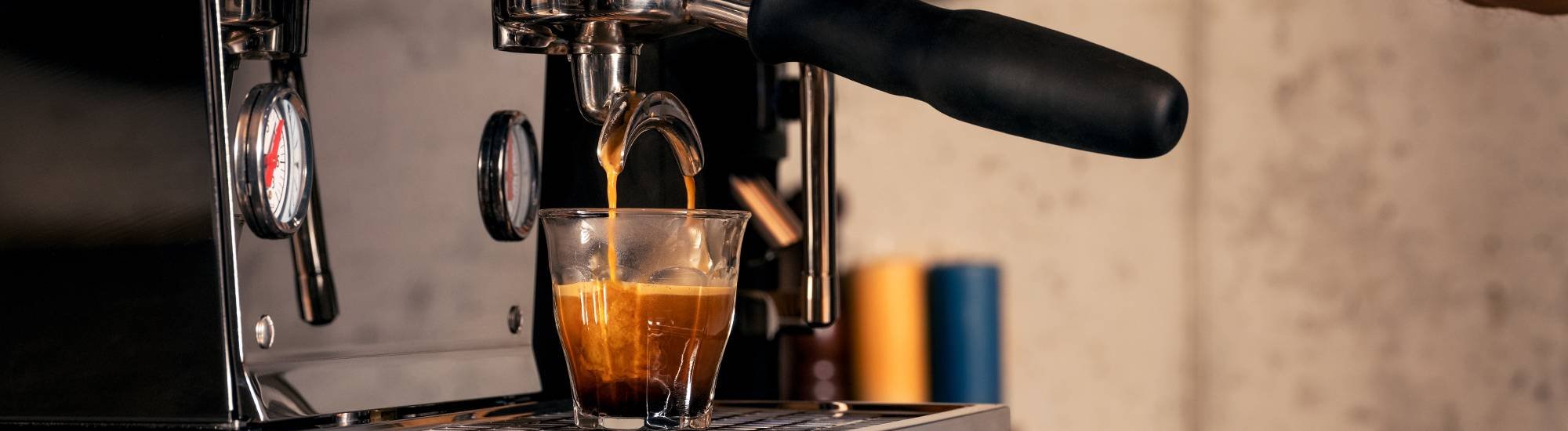 eine Siebträger Maschine bereitet einen Kaffee zu, Kaffee läuft in ein Glas