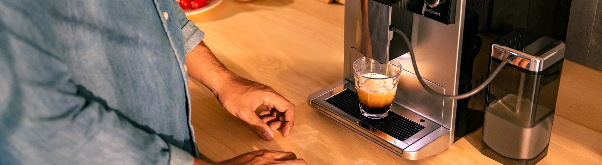 ein Kaffeevollautomat bereitet einen Kaffee zu, Kaffee läuft in ein Glas