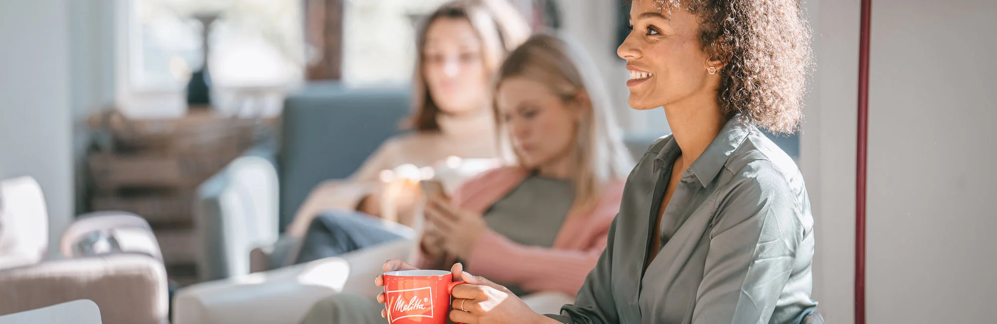 Photo of a smiling woman with a red Melitta mug in her han