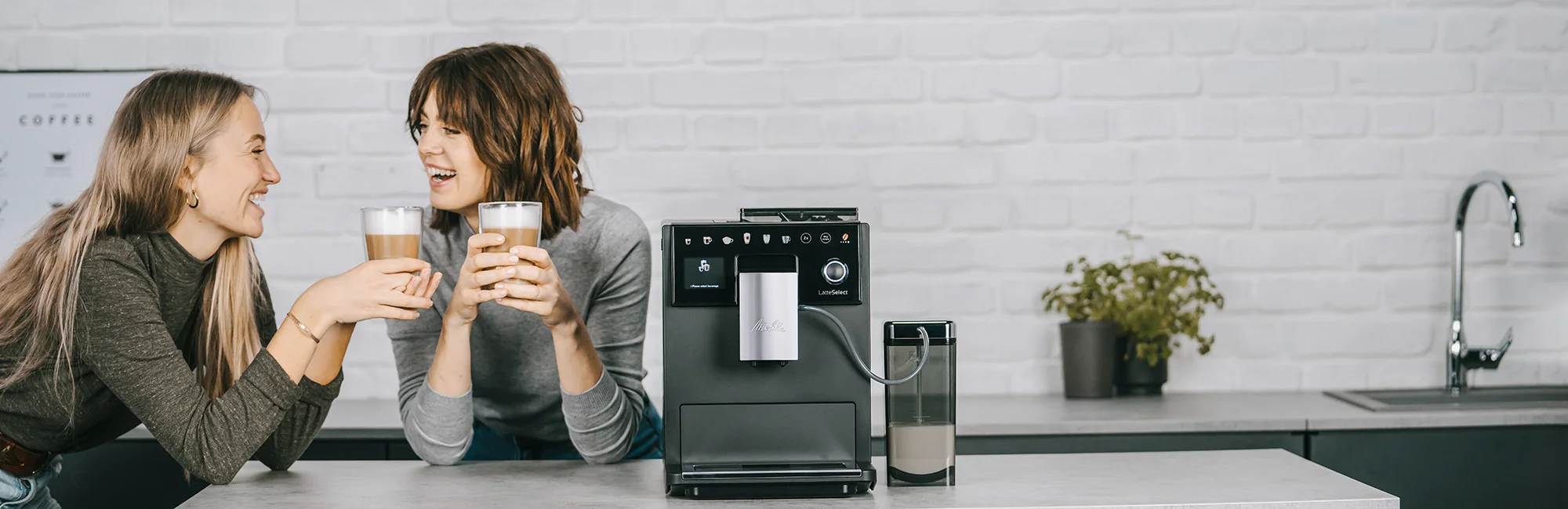 Two models drinking coffee beside a Melitta LatteSelect black