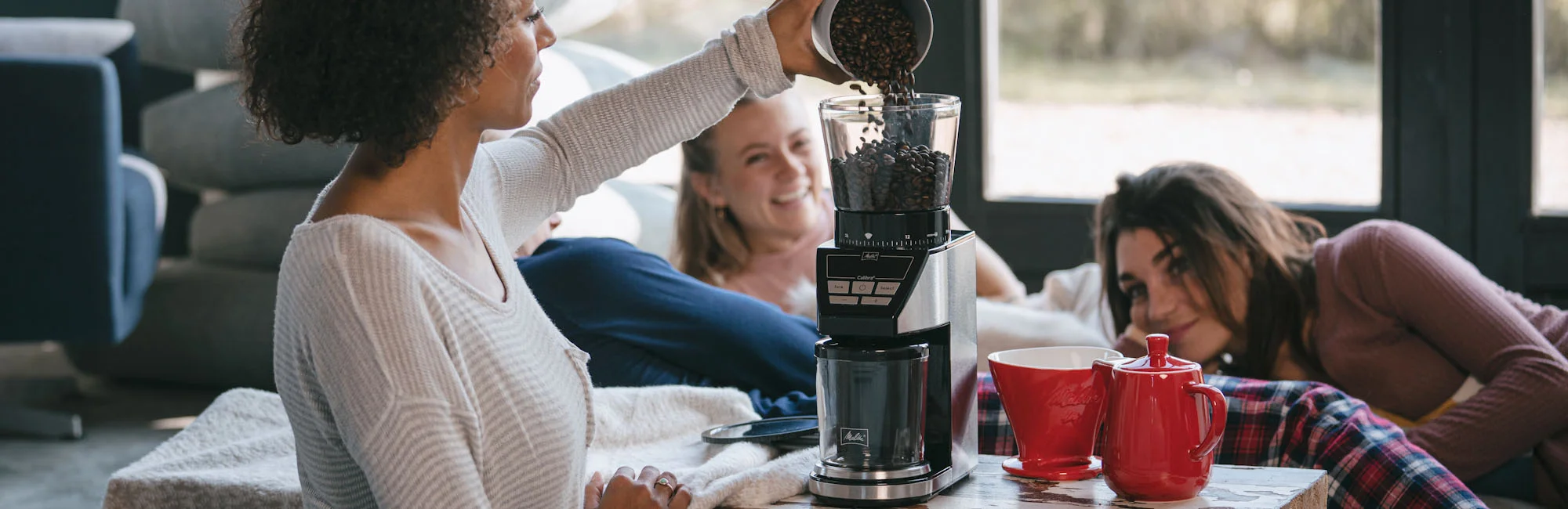 Afbeelding van een persoon die koffie in onze koffiemolen genaamd Calibra giet