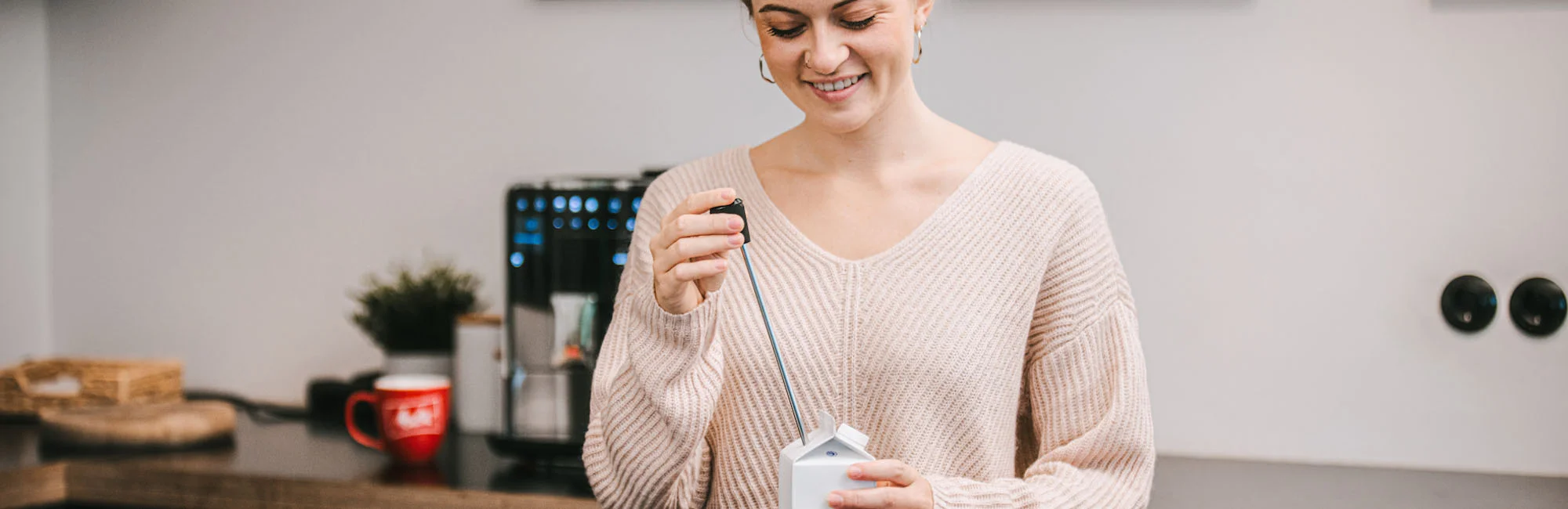 Image of a woman inserting a tube into her milk carton to create creamy milk froth with our automatic espresso machine