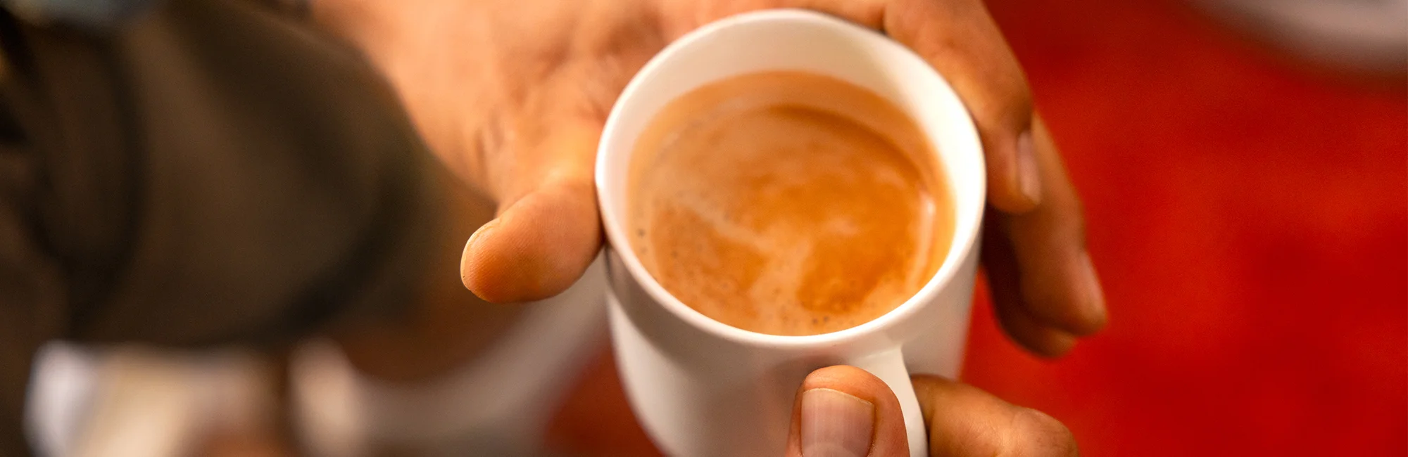 Eine Tasse Kaffee Crema wird in Händen gehalten