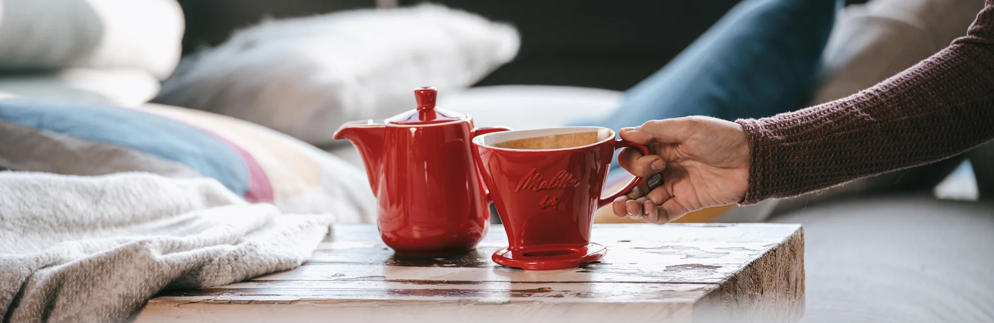 roter Handfilter und rote Porzellan Kaffeekanne auf einem kleinen Tisch