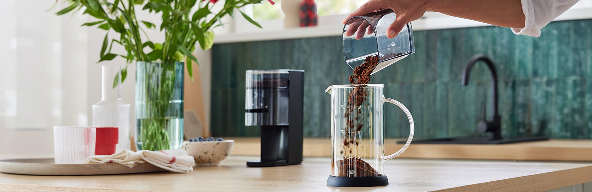 Melitta Linea® Kaffeemühle und gemahlener Kaffee in einer Glaskaraffe.