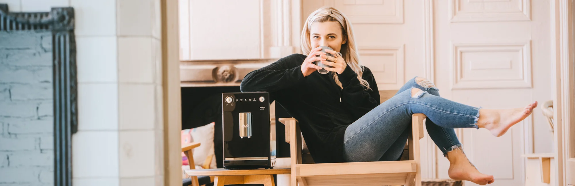 En kvinna sitter på en trästol och njuter av sitt Melitta-kaffe.