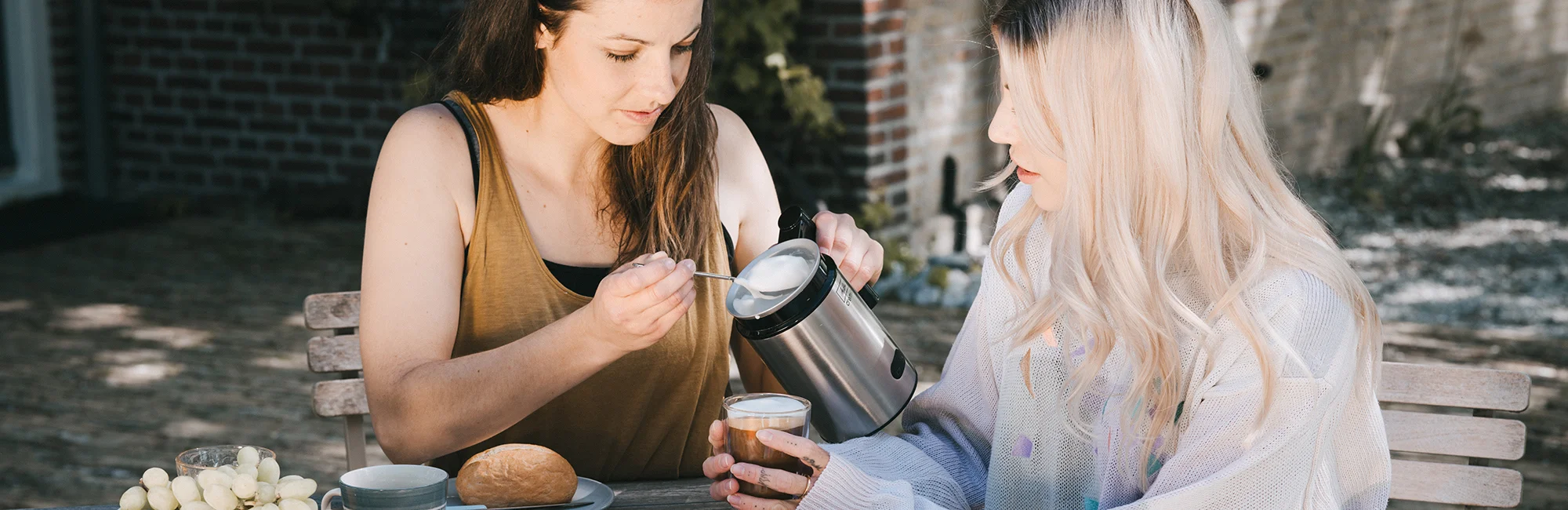 Image of 2 women using our cream to make milk foam.