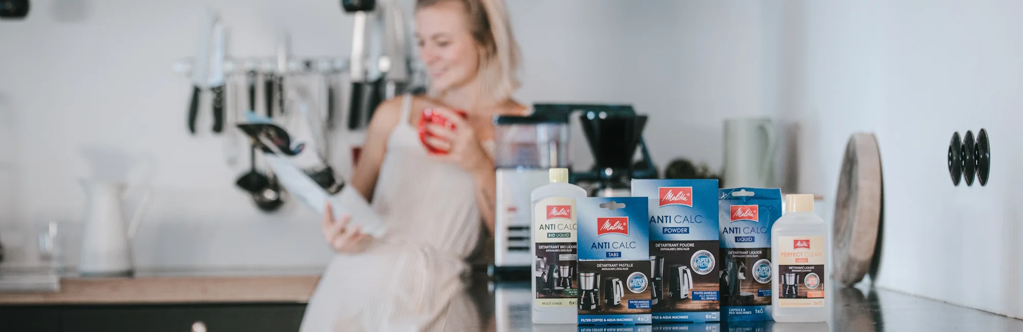 Different descaler in a kitchen, woman in the background 