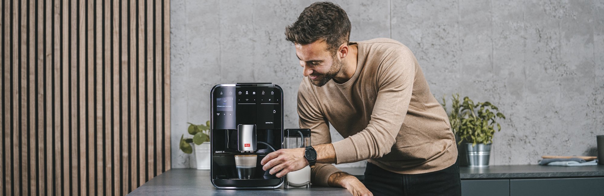 Man gebruikt een Melitta Barista T Smart met melkreservoir in een moderne keuken