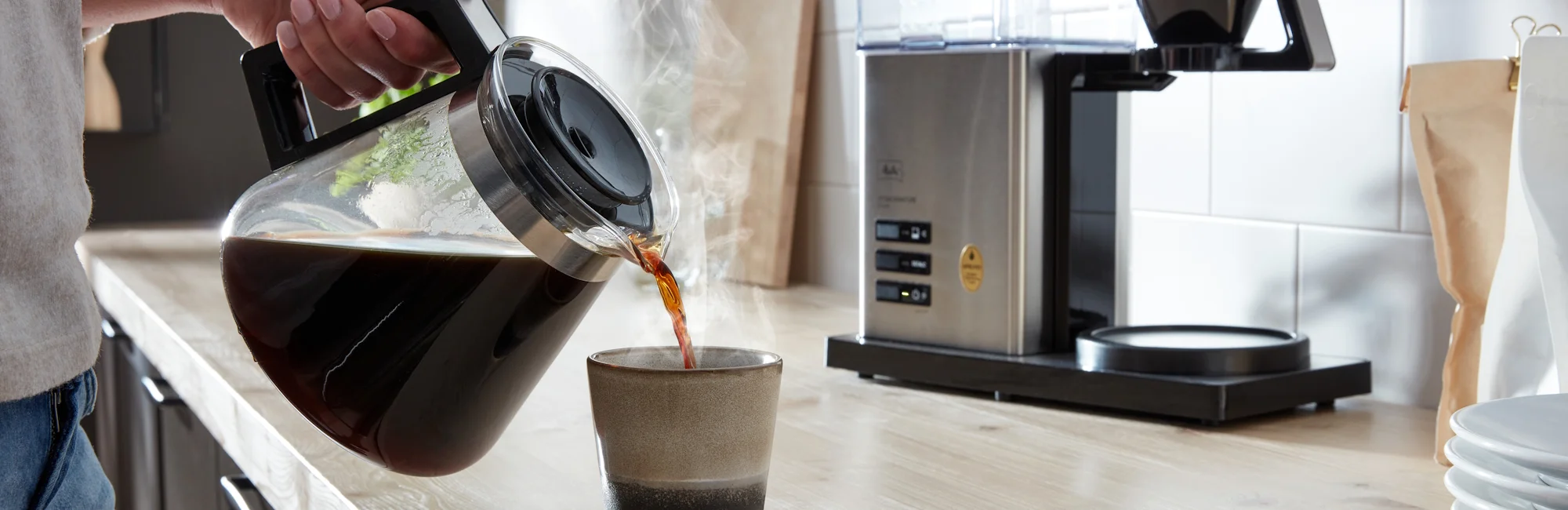 Filter coffee is poured from a pot into a cup