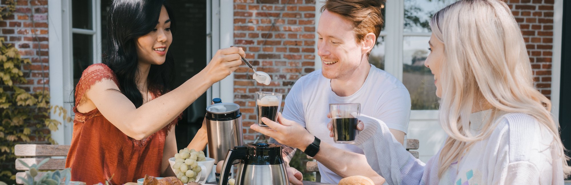 Photo of 3 friends enjoying a good coffee topped with creamy milk foam made with our Cremio milk frother.