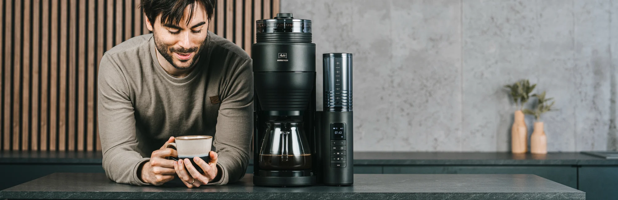 Image of a man having coffee with our Aromafresh machine and its built-in grinder.