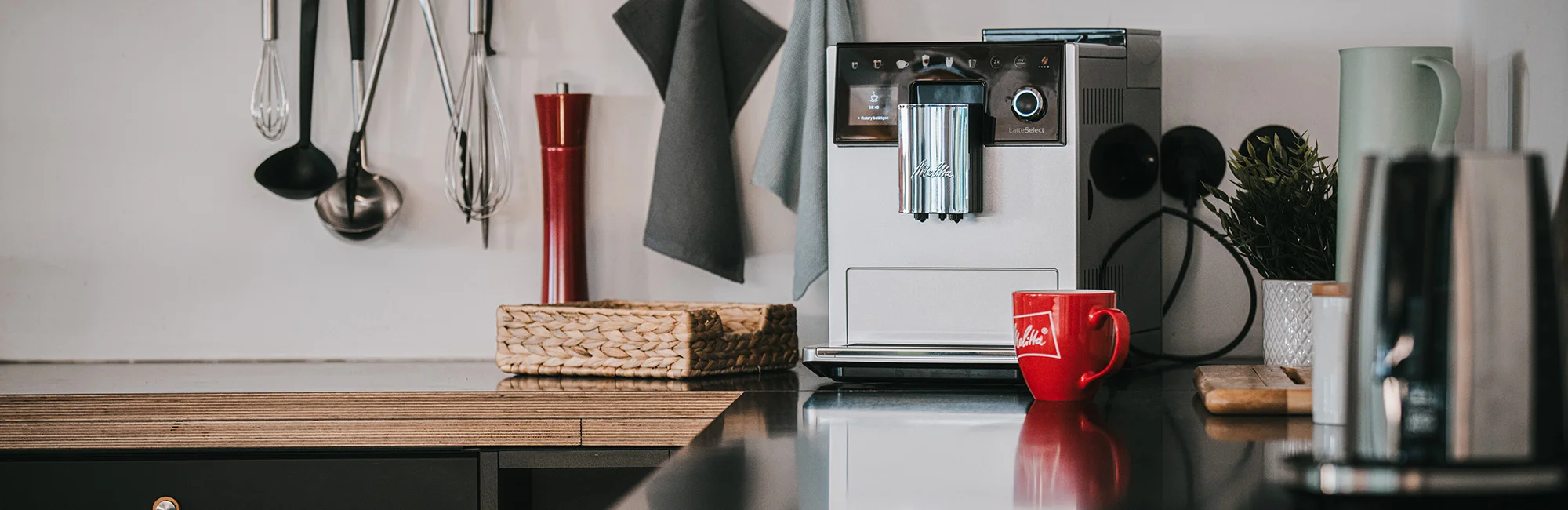 Der Melitta Kaffeevollautomat Latte Select steht auf einer Küchenzeile.