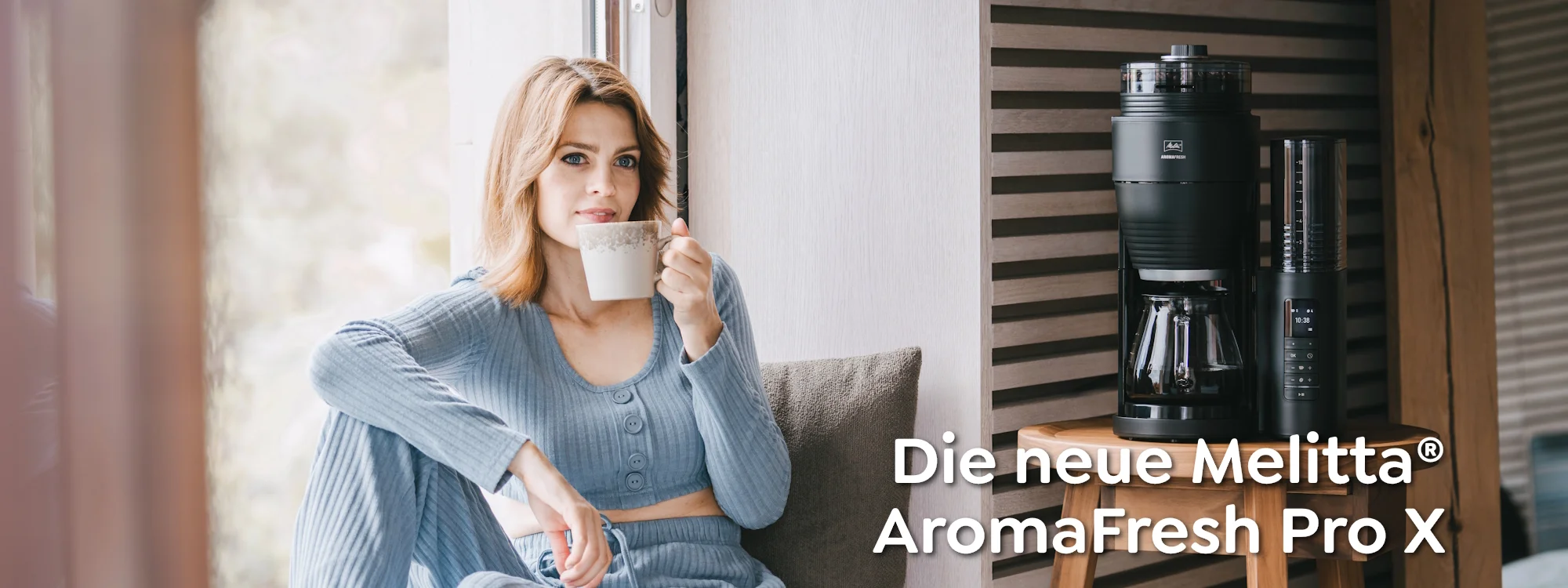 Eine Frau genießt ihren Kaffee aus der neben ihr stehenden Melitta AromaFresh Pro X Filterkaffeemaschine