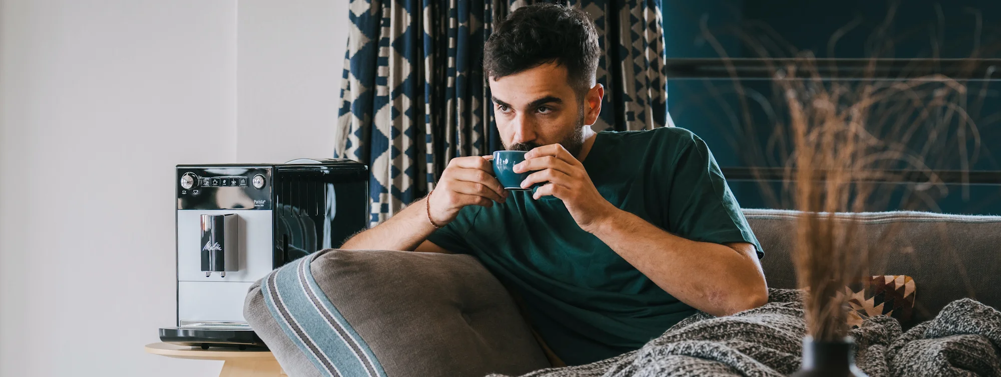 Man zit op een bank met een kopje koffie uit de Melitta Purista.