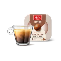 Kaffeetasse aus Glas gefüllt mit Kaffee vor Verpackung der Melitta®  BellaCrema La Crema coffeeb Verpackung