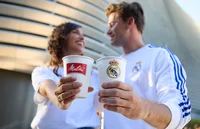 Real Madrid fans laughing at each other while holding Melitta cups