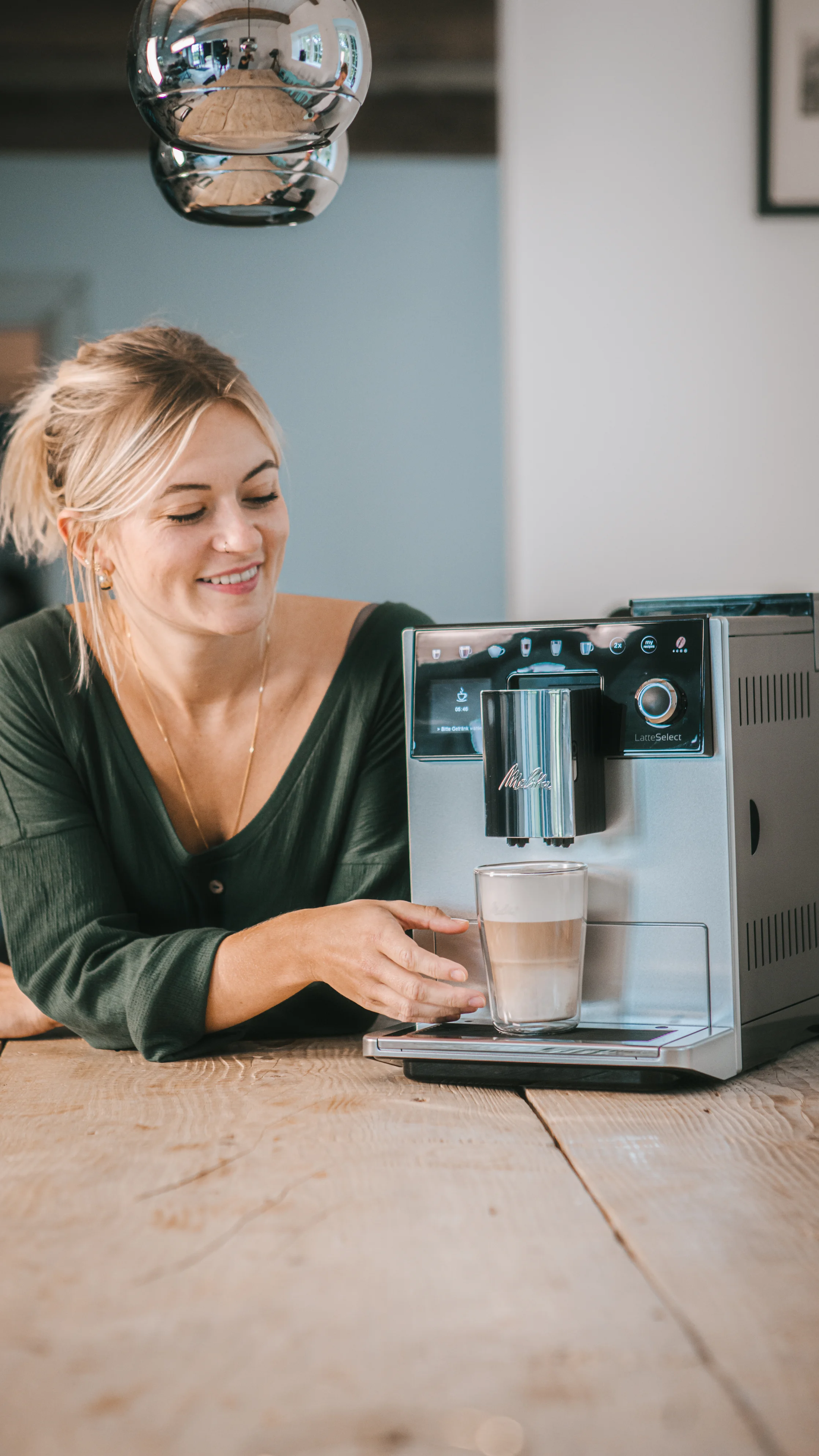 Image of a smiling woman in front of her freshly brewed coffee made with our Latte Select machine.