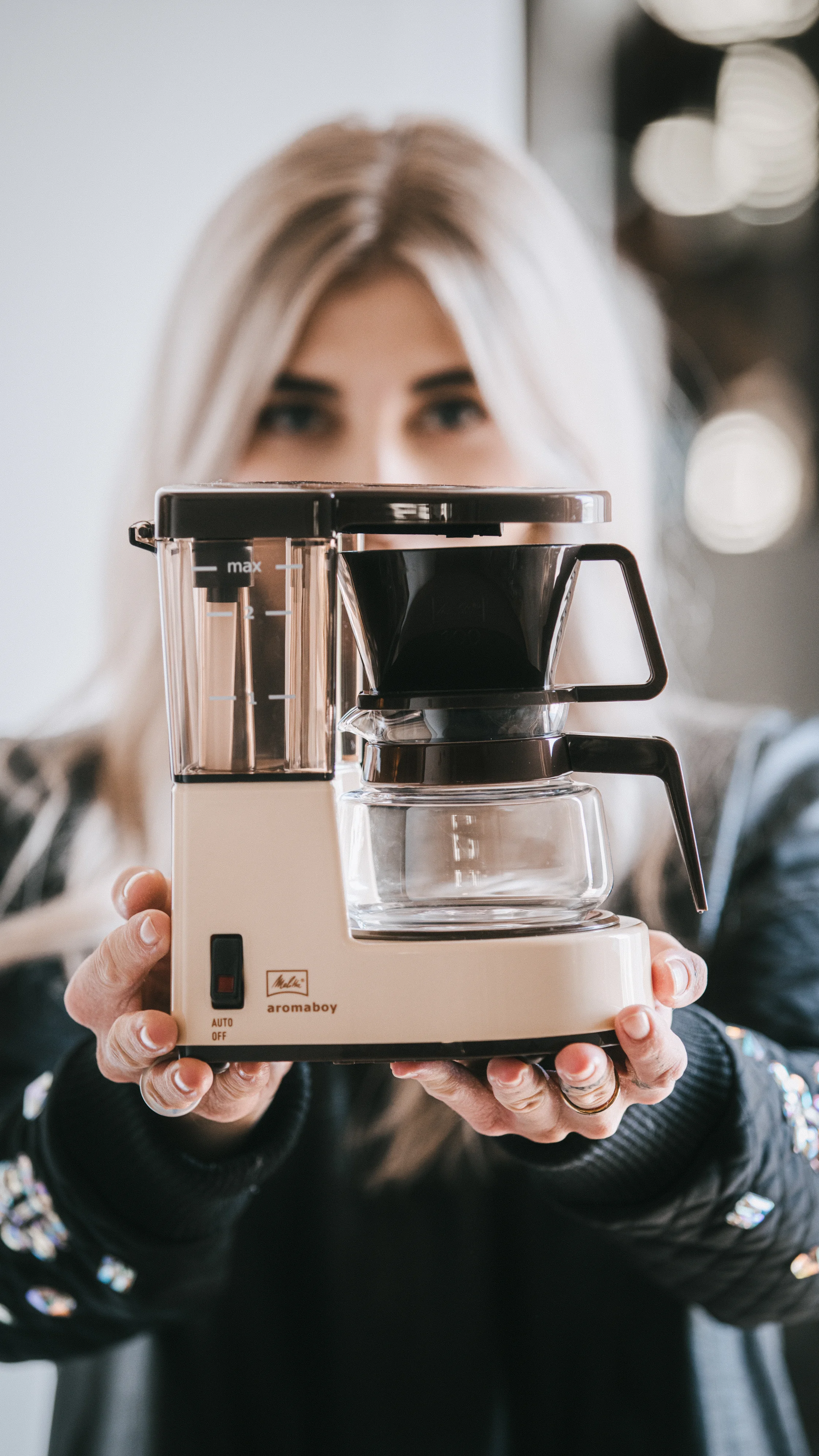 Frau hält eine beige Melitta Aromaboy Filterkaffeemaschine mit beiden Händen nach vorne