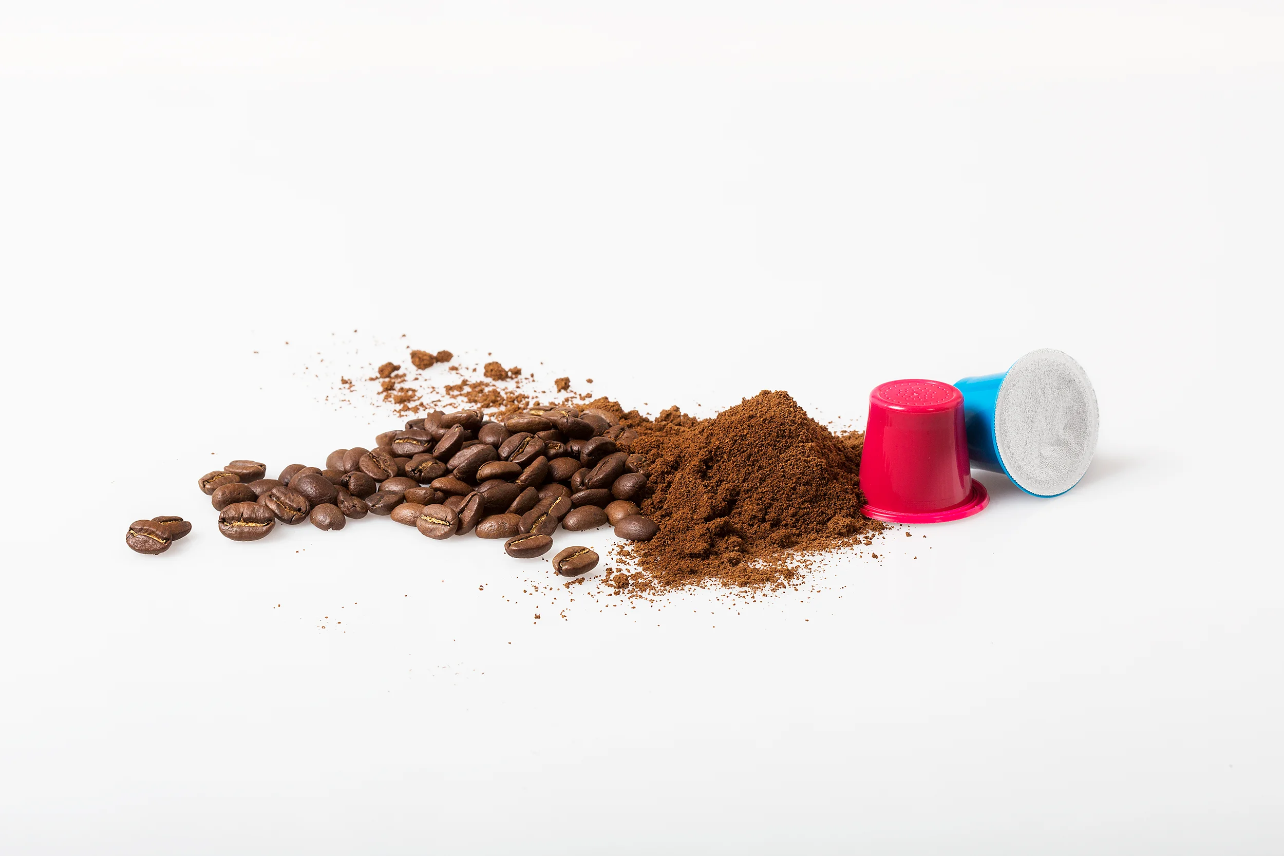 Kaffeebohnen, gemahlener Kaffee und zwei Kaffeekapseln