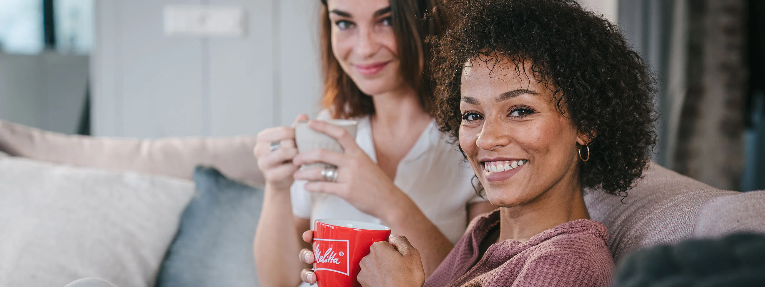 Zwei Frauen genießen Melitta Kaffee auf der Couch