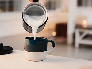 Mælkeskum hældes fra Melitta® Cremio® i et keramikkrus