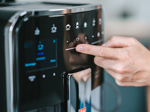 Cafetera Melitta Barista T Smart con un dedo seleccionando una bebida en el panel táctil