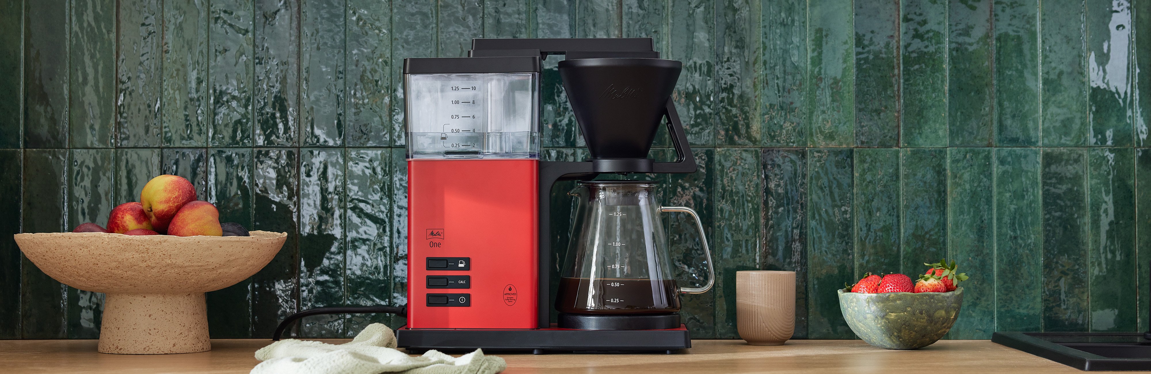 Melitta® One auf Kücheninsel und Zwei Menschen stehen mit Tasse drum rum