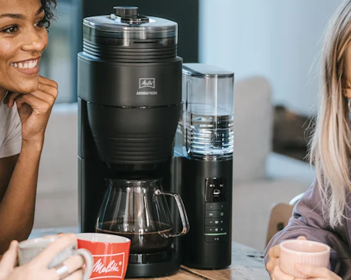Twee mensen met koffiemokken voor het Melitta AromaFresh Pro filterkoffiezetapparaat
