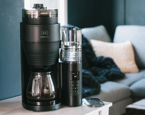 Melitta AromaFresh Pro Filterkaffeemaschine mit Waage auf Beistelltisch im gemütlichen Wohnzimmer.