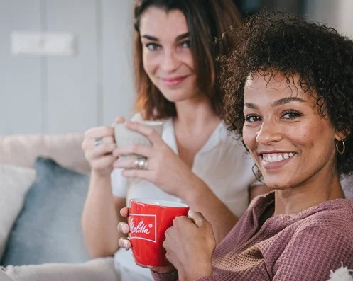 two women drinking melitta coffee on the couch