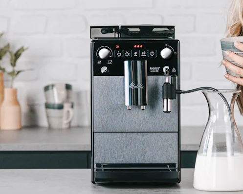 Melitta Avanza steht auf einem Tisch in der Küche, und eine Frau rechts danaben