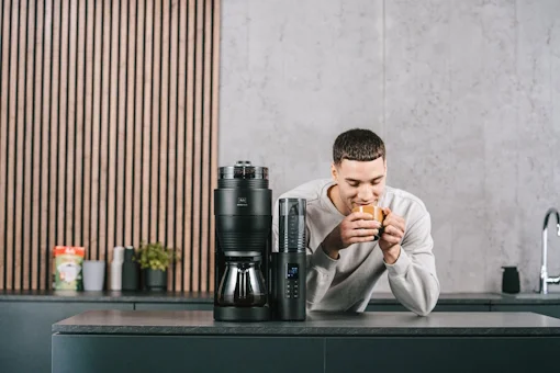 Mann genießt eine Tasse Kaffee neben der Melitta® AromaFresh X Filterkaffeemaschine in moderner Küche