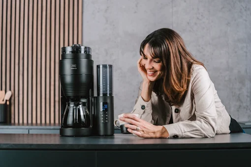 Kvinna ler och dricker kaffe bredvid Melitta AromaFresh Pro