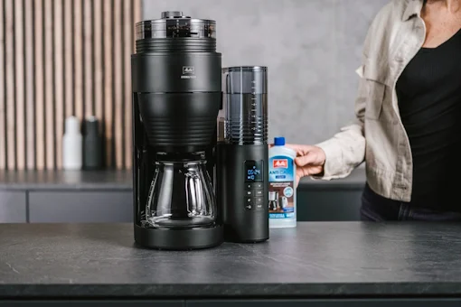 Kvinna ställer Melitta Anti Calc bredvid AromaFresh Pro filterkaffebryggaren