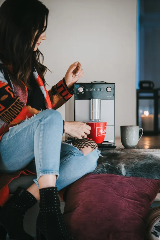 Frau genießt Kaffee mit einer Melitta CI Touch und roter Melitta Tasse in gemütlicher Atmosphäre