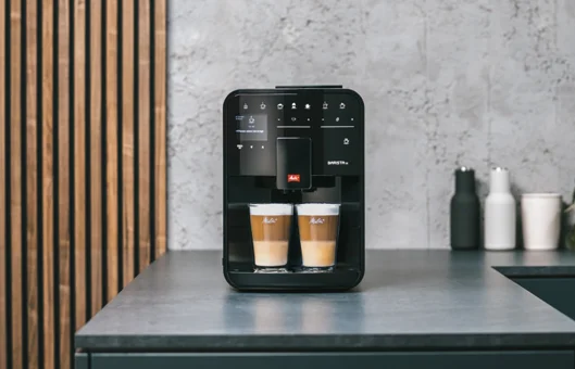 Melitta Barista T Smart coffee machine preparing two layered latte macchiatos in a modern kitchen