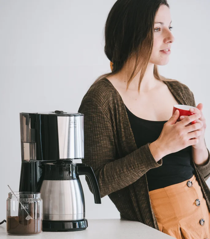 Melitta Enjoy Top Therm kaffemaskine ved siden af kvinde med rød kop.