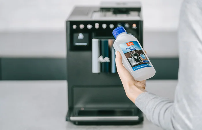 Eine Frau hält Entkalker für den Melitta Kaffeevollautomaten in der Hand