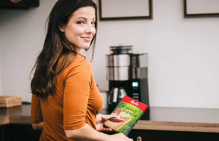 image d'une femme dans sa cuisine  prête à essayer nos filtres à café Coffee Coach
